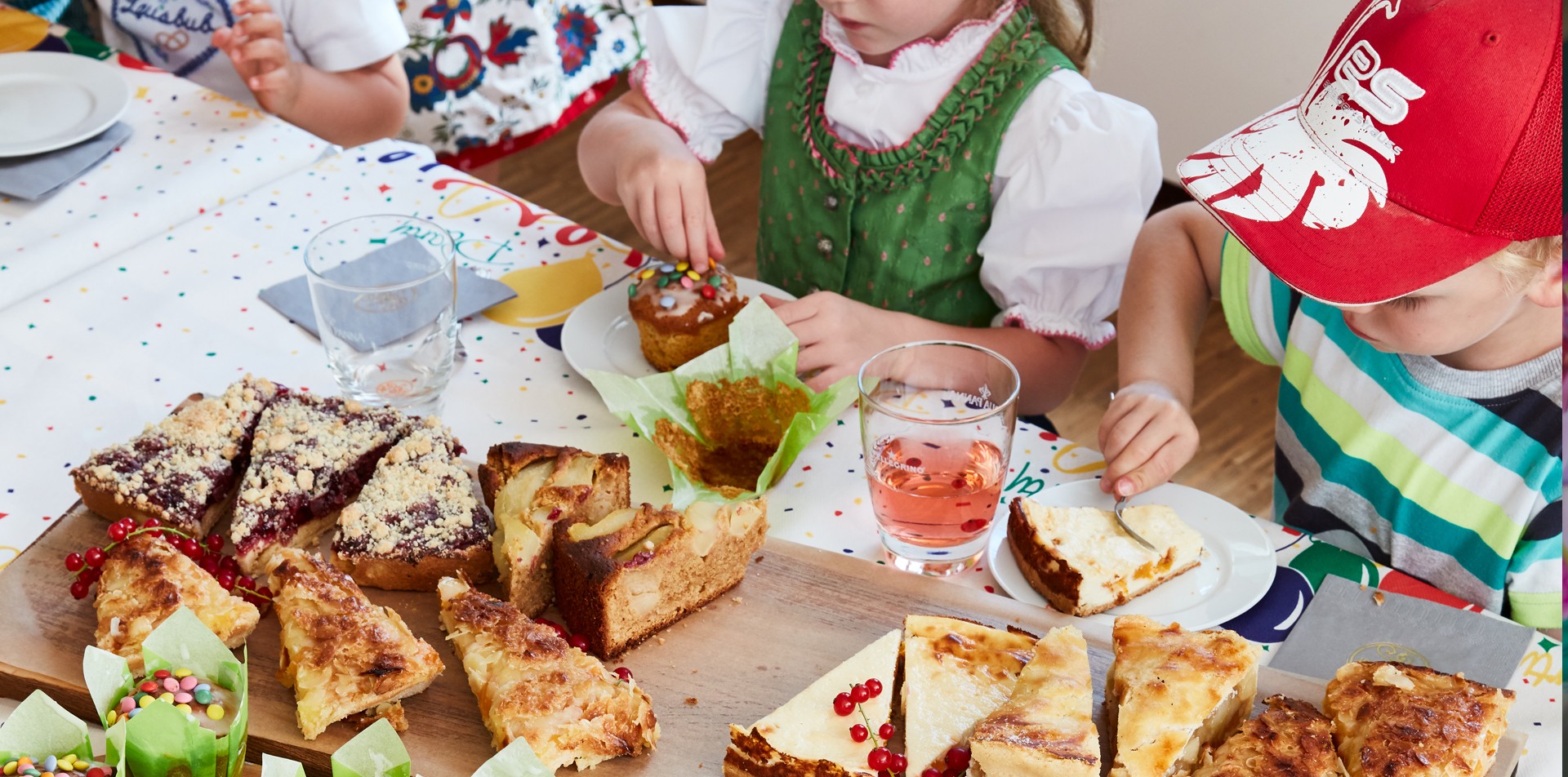 Kinder essen Geburtstagskuchen an einem dekorierten Geburtstagstisch